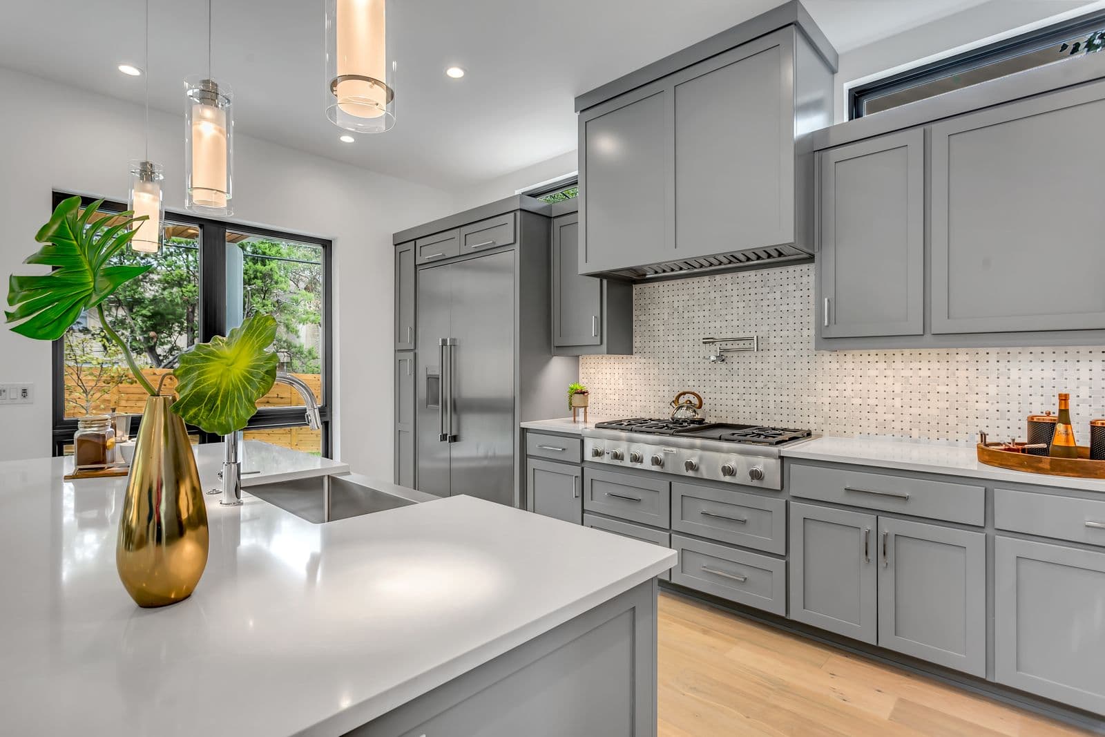 Custom gray shaker cabinetry with full-height uppers and an integrated range hood surround