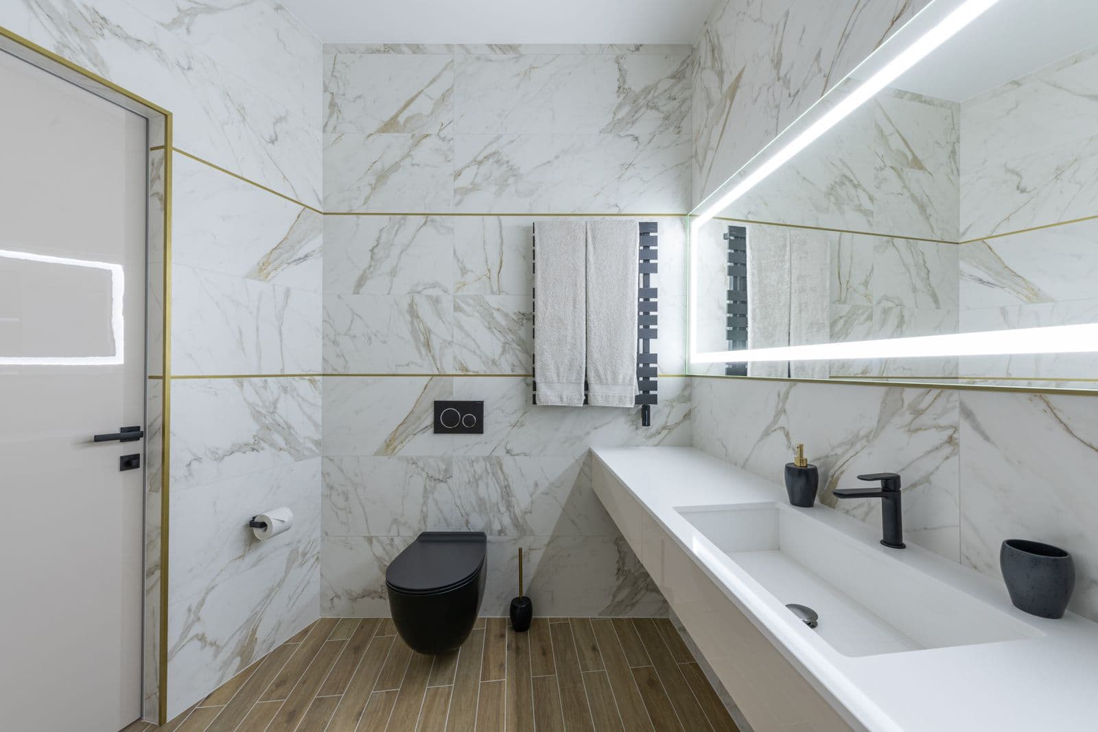 Compact remodeled bathroom with marble-look tile, floating vanity, and brass trim details