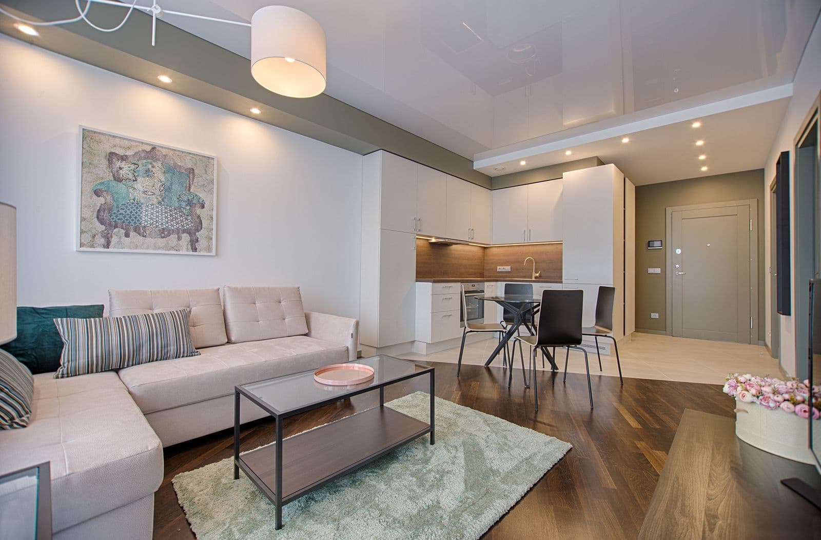 Open-plan condo kitchen with white cabinetry and wood-accent backsplash in a high-rise unit